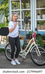 A Happy Mature Woman Eating Ice-cream And Looking Enjoyed