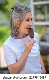 A Happy Mature Woman Eating Ice-cream And Looking Enjoyed