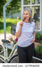 A Happy Mature Woman Eating Ice-cream And Looking Enjoyed