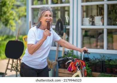 A Happy Mature Woman Eating Ice-cream And Looking Enjoyed