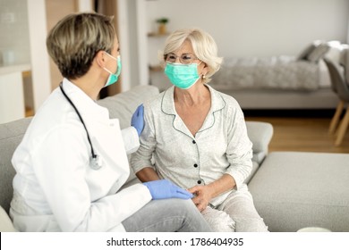 Happy Mature Woman And Female Doctor Wearing Protective Face Masks During A Home Visit. 