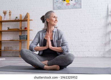 Happy Mature Woman With Grey Hair Sitting With Praying Hands In Lotus Pose On Yoga Mat