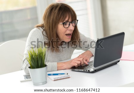 Happy mature woman having an amazing surprise on laptop