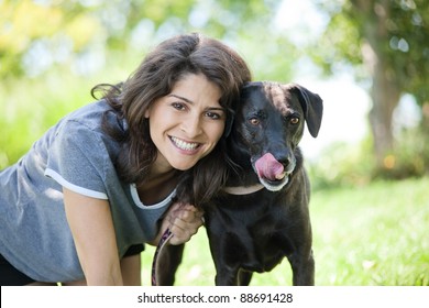 Happy Mature Woman With Her Black Labrador Retriever Dog In The Yard