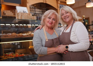 Happy mature woman hugging her senior mother, working together at their bakery store - Powered by Shutterstock