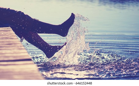 happy mature woman at a lake having fun and splashing water in summer