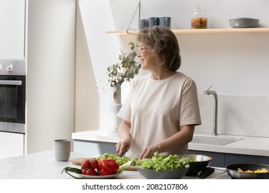 Happy Mature Woman Making Salad In Kitchen, Thinking Over Main Course, Family Dinner Menu, Looking Away, Cutting Fresh Vegetables, Keeping Healthy Diet For Weight Loss, Preparing Organic Food