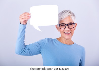 Happy Mature Woman In Plain Blue Long Sleeve T-shirt Holding Empty Speech Bubble Isolated On Background. Woman Showing Sign Speech Bubble Banner Looking Happy