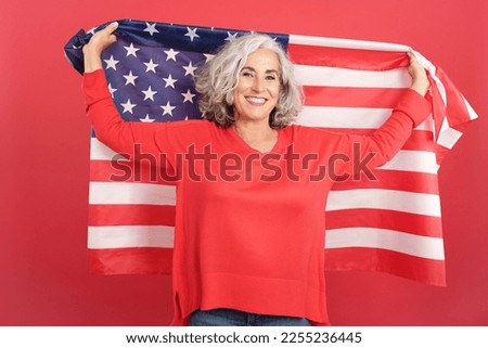 Happy mature woman raising a north america national flag