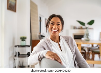 Happy Mature Woman Relaxing On Her Couch At Home In The Living Room. Beautiful Young Woman Laughing Alone In Living Room. Beautiful Smiling African Lady Sitting On Sofa.