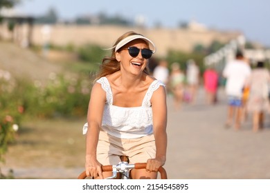 Happy Mature Woman Riding Bicycle In City Park On Summer Day