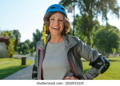 Happy Mature Woman Rollerblading In The Park Wearing Helmet, Protective Helmet, Knee Pads, Elbow Pads