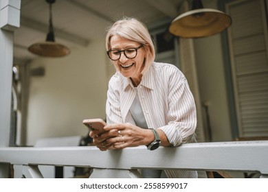 happy mature woman stand on the restaurant terrace and use mobile phone