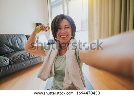 Happy mature woman taking a selfie at workout gym at home during quarantine. Concept about people, gym at home, sport.