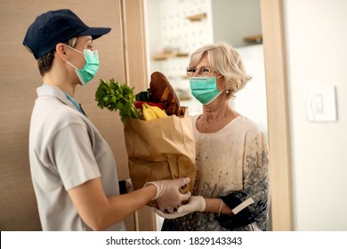 Happy Mature Woman Talking To Female Courier While Receiving Groceries  At Home During COVID-19 Pandemic. 