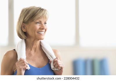 Happy Mature Woman With Towel Around Neck Looking Away At Home