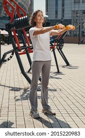 Happy Mature Woman Training Shoulders In Open Air