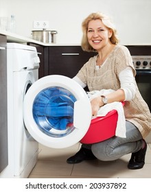 Happy Mature Woman Using Washing Machine At Home Laundry