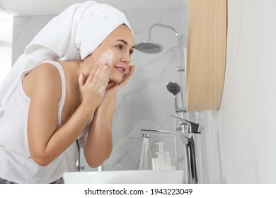 Happy Mature Woman Washing Face In Bathroom