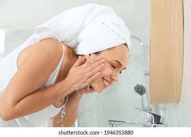 Happy Mature Woman Washing Face In Bathroom