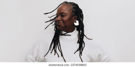 Happy mature woman whipping her dreadlocks confidently while standing against a white background. Body positive black woman embracing her natural hair. - Powered by Shutterstock