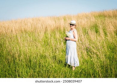 Happy mature woman with wildflowers in a tall grass field on a bright summer day. - Powered by Shutterstock