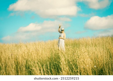 Happy mature woman with wildflowers in a tall grass field on a bright summer day. - Powered by Shutterstock