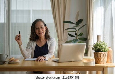 Happy Mature Woman Working Online, Checking Email Laptop Computer While Sitting In Bright Living Room.