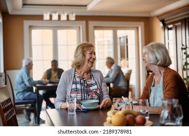 Happy Mature Women Having Fun During Conversation In Dining Room Of Nursing Home. 