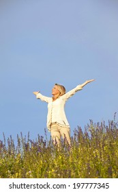 Happy Matured Woman In A Meadow With Spread Arms