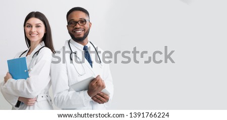 Happy Medic Workers. Portrait Of Two Doctors In White Coats Over White Background, Copy Space
