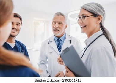 Happy medical staff talking in hospital corridor, having briefing about patients complaints, medical history, treatment and healing. Healthcare and medicine - Powered by Shutterstock