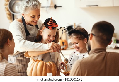 Happy Members Of Multi Generational Family With Pumpkins Gathering Around Table And Preparing For Halloween Celebration In Kitchen At Home
