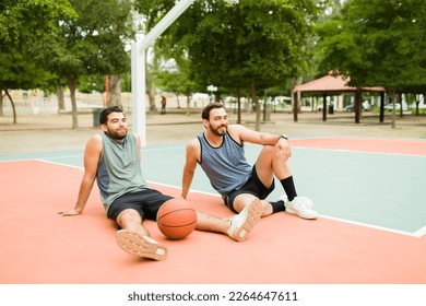 Happy men friends resting and taking a break after playing a fun basketball game at the park - Powered by Shutterstock