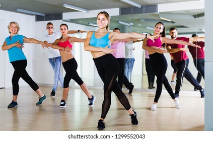 happy men and ladies dancing aerobics at lesson in the dance class