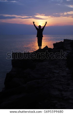 Happy men sihouette with arms raised up in success on sunset glow sunshine banner panorama. Wellness, financial freedom, healthy life concept background. 