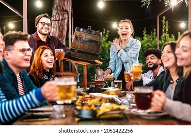 Happy men and women having fun drinking out at beer garden - Social gathering life style concept on young people enjoying weekend hangout time together at night - Warm dark filter