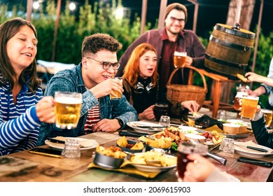 Happy men and women having fun drinking beer at patio garden fest - Social gathering life style concept on young friends enjoying hangout time together at night - Warm filter with focus on left guy - Powered by Shutterstock