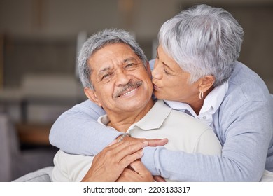 Happy Mexico Senior Couple Kiss On Living Room Sofa For Love, Care And Trust In Romantic Relationship At House Or Home. Elderly People Or Retirement Man And Woman Smile, Hug And Kissing Face Cheek