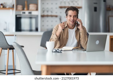 Happy Mid Adult Businessman Talking To Someone Over Mobile Phone While Working At Home Office.