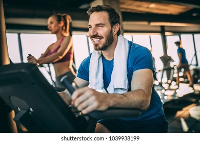 Happy Mid Adult Man Having Fun In The Gym. Bicycle For Better Cardio Workout.