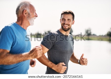 Happy mid adult man jogging with his mature father in nature.