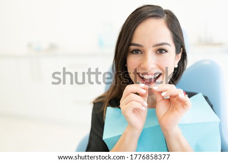 Happy mid adult woman with clear orthodontic retainer in dental clinic
