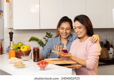 Happy mid adult woman and her mother making healthy fruit sandwich in the kitchen. - Powered by Shutterstock