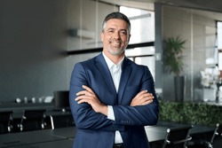 Happy Mid Aged Business Man Ceo Standing In Office Arms Crossed. Smiling Mature Confident Professional Executive Manager, Proud Lawyer, Confident Businessman Leader Wearing Blue Suit, Portrait.