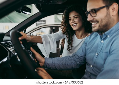 Happy Middle Age Couple Enjoying While Choosing And Buying New Car At Showroom.