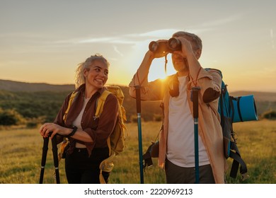 Happy middle age couple on hiking trip on summer holiday, using binoculars - Powered by Shutterstock