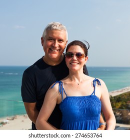 Happy Middle Age Couple On A Balcony Overlooking Miami Beach.