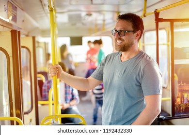 Happy middle age man holding for a bar in a bus and smiling. Waiting for bus to move on.