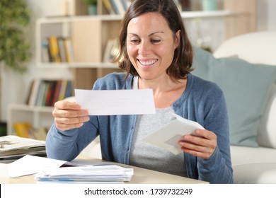 Happy middle age woman opening receipts letters sitting in the livingroom at home